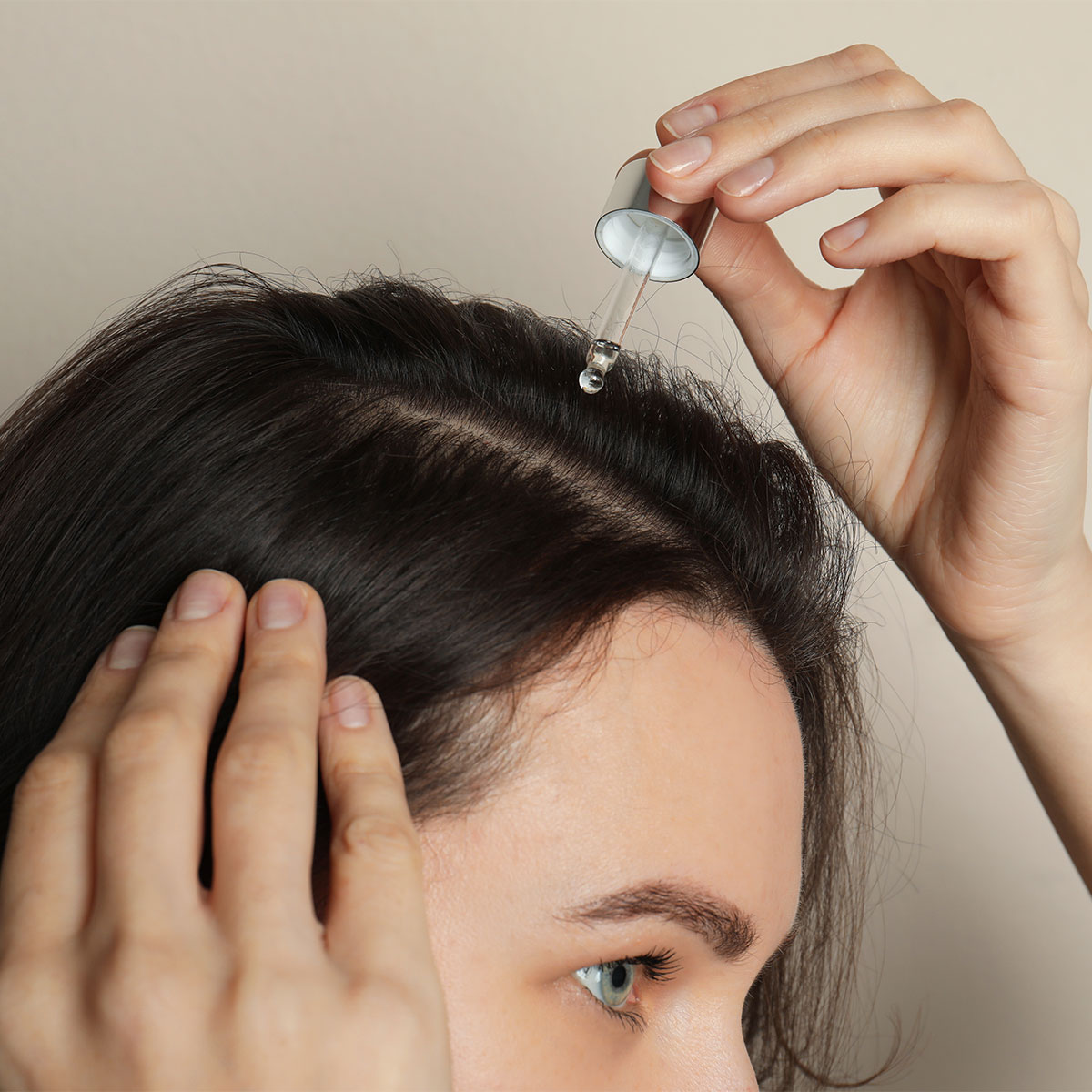 dark haired girl applying serum to scalp